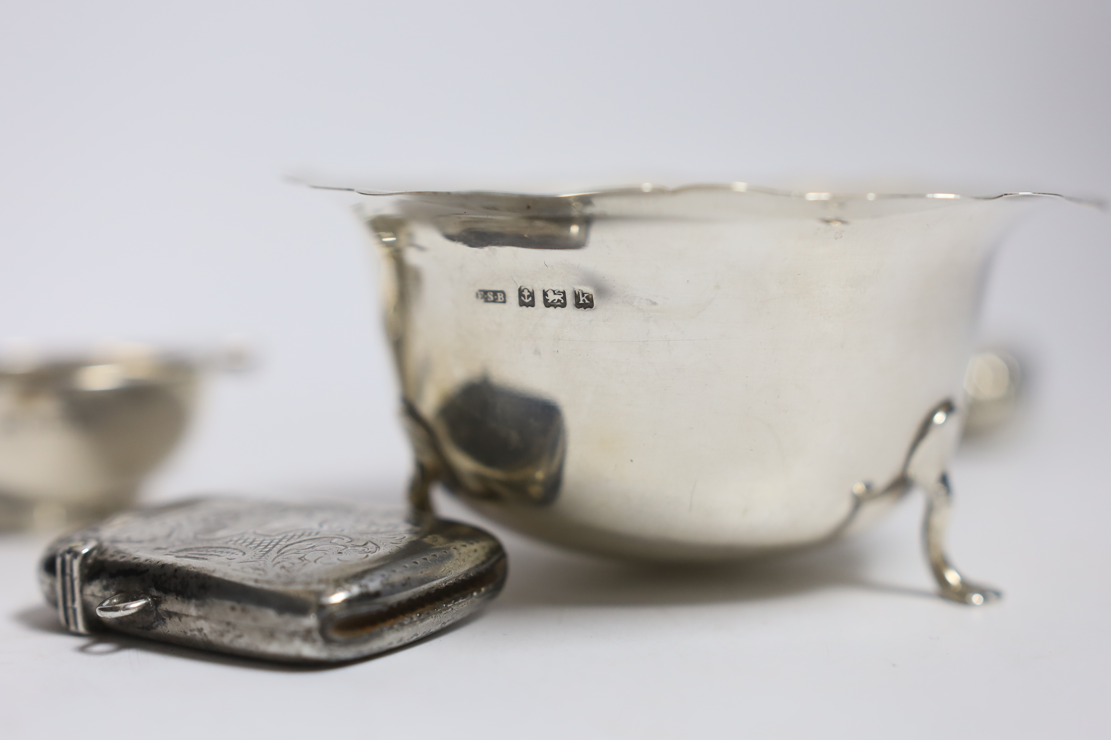 A silver cigarette case, small silver quaich, silver bowl and silver matchbox sleeve.
